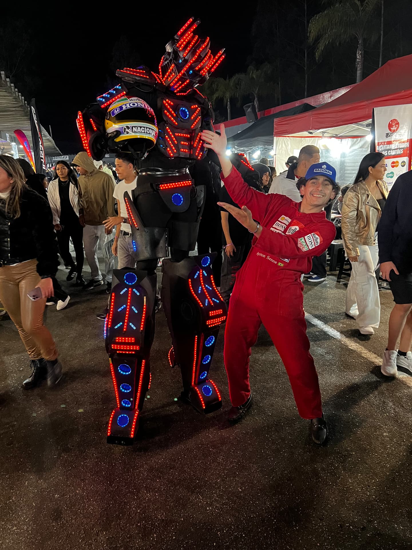 Robô de LED posando com convidado fantasiado em evento noturno